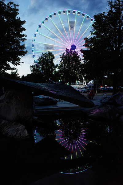 There was a ferris wheel on the parking lot on the other side of the street which started to be colorful before it went dark but stopped being lit when it really became dark. I took this picture just a few seconds - maybe 2 seconds - before the colors were turned off. The photographer next to me tried to take the same picture at the same time but was two seconds slower and didn't get it. Mine didn't turn out exactly how I intended. I could probably fix it if I developed the raw image.